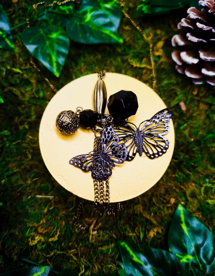 Collier sautoir orné de papillons métalliques et de perles facettées noirs